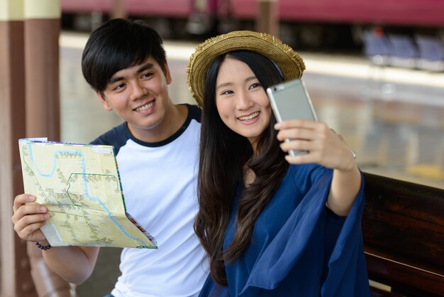 Porträt des jungen philippinischen Touristenmannes und der jungen asiatischen Touristenfrau zusammen und verliebt am Bahnhof Hua Lamphong