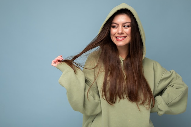 Porträt des jungen schönen lächelnden Mädchens in der sexy sorglosen Frauenaufstellung des stilvollen Hippie-grünen Hoodies