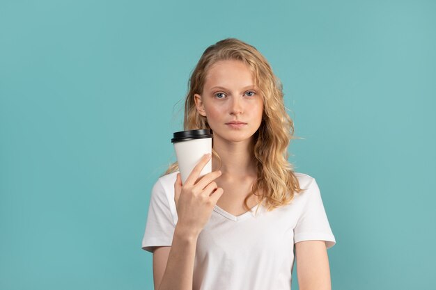 Porträt des jungen Studentenmädchens mit Tasse Kaffee auf grüner Wand