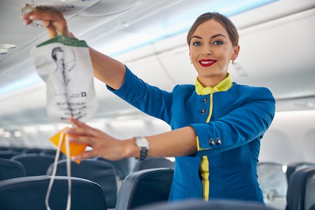 Porträt des Kabinenpersonals, das die Sauerstoffmaske während der Sicherheitsdemonstration an Bord kommerzieller internationaler Fluggesellschaften hochhält