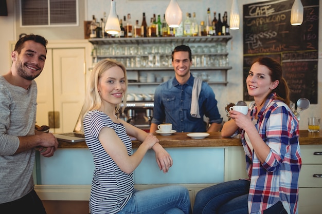 Porträt des Kellners mit glücklichen Kunden am Café