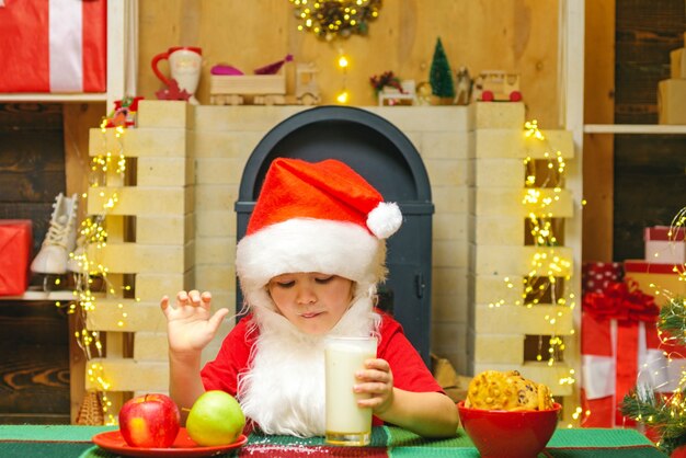 Porträt des Kindes Santa Claus Milch aus Glas trinken und Kekse halten.