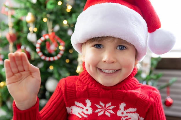 Porträt des Kindes zu Weihnachten Lustiger Kindergruß im Video-Chat-Weihnachtsfeiertagskonzept