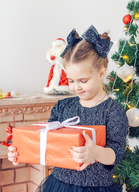 Porträt des kleinen glücklichen netten Mädchens mit Weihnachtsgeschenk.