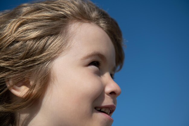 Porträt des kleinen Jungen, der auf blauem Himmel mit Kopienraum, Gesichtsnahaufnahme wegschaut. Kopf schießen Kinderportrait.