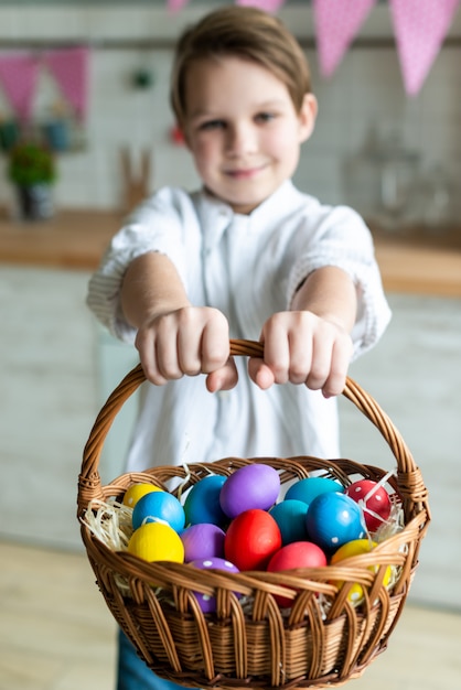 Porträt des kleinen Jungen, der einen Korb mit Ostereiern hält / Fokus auf Korb