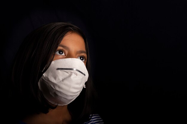 Porträt des kleinen Mädchens, das eine medizinische Maske trägt, die zum Virenschutz verwendet wird
