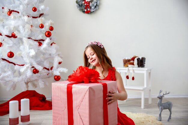 Porträt des kleinen netten Mädchens mit Weihnachtsgeschenk