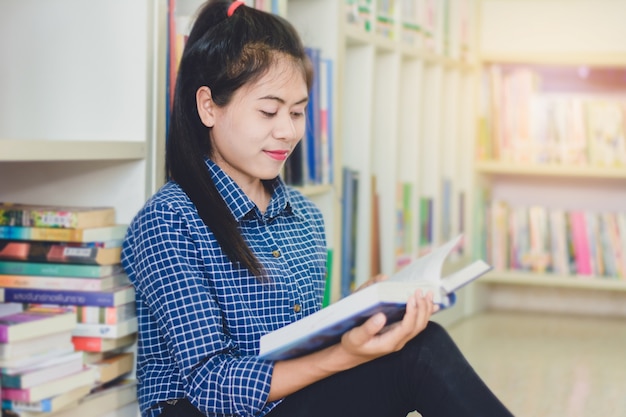 Porträt des klugen asiatischen Studenten, der Forschung in der Collegebibliothek liest und tut