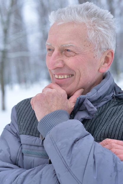 Porträt des lächelnden älteren Mannes, der im Winter draußen steht