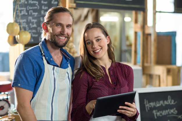 Porträt des lächelnden Bäckereipersonals unter Verwendung der digitalen Tablette am Schalter