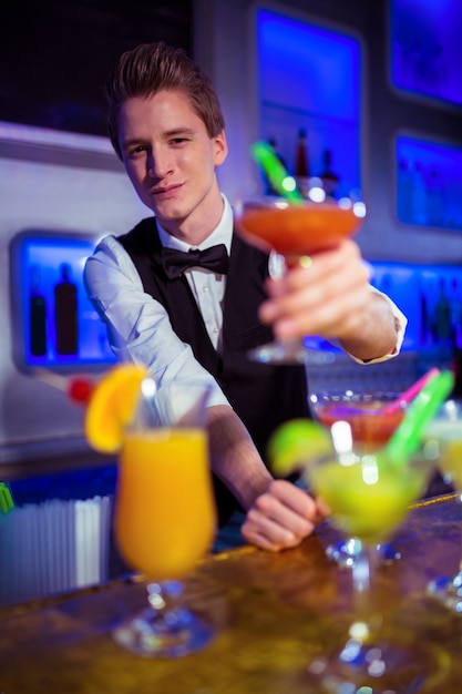 Foto porträt des lächelnden barkeepers, der cocktailglas hält