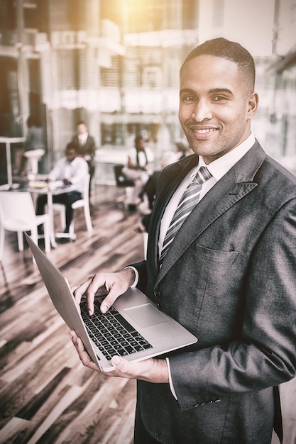Porträt des lächelnden Geschäftsmannes unter Verwendung des Laptops