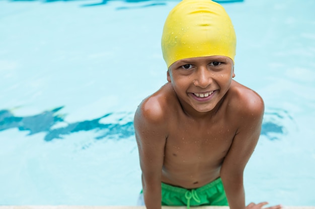 Porträt des lächelnden Jungen, der im Schwimmbad steht