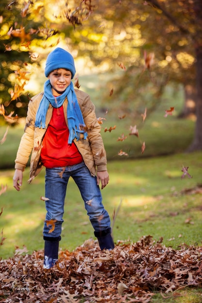 Porträt des lächelnden Jungen mit Herbstlaub