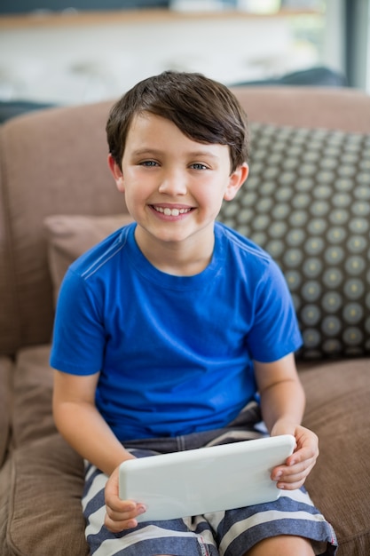 Porträt des lächelnden Jungen unter Verwendung der digitalen Tablette im Wohnzimmer