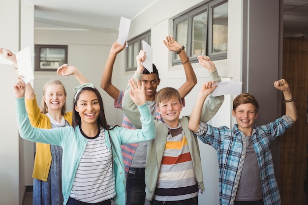 Porträt des lächelnden Klassenkameraden, der mit der Hand im Korridor angehoben steht