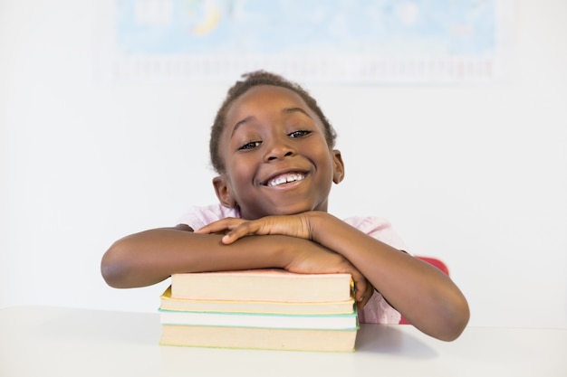 Porträt des lächelnden Mädchens mit Büchern im Klassenzimmer