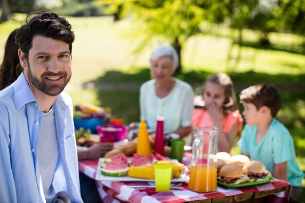 Porträt des lächelnden Mannes, der im Park sitzt