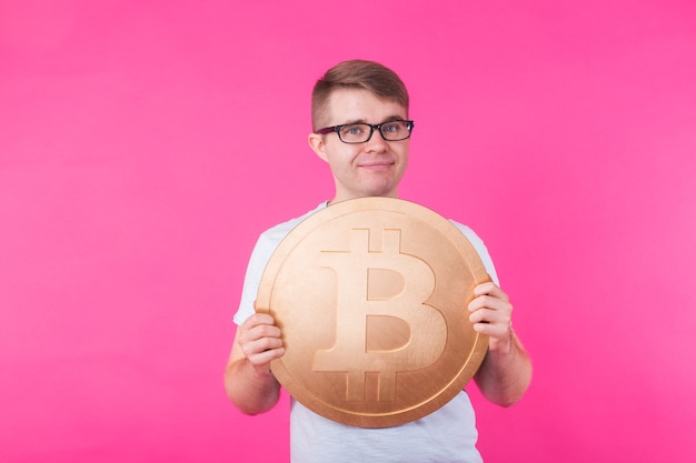 Porträt des lächelnden Mannes mit großem Bitcoin auf rosa Wand