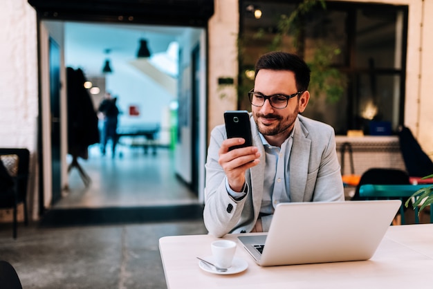 Porträt des lächelnden Mannes Smartphone am Café betrachtend.