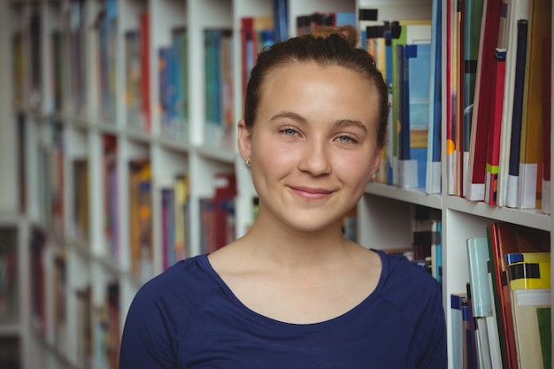 Porträt des lächelnden Schulmädchens, das in der Bibliothek lächelt