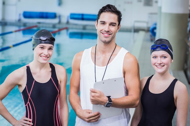 Porträt des lächelnden Trainers und der Schwimmer im Freizeitzentrum