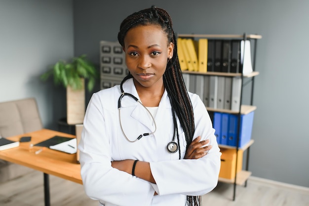 Porträt des lächelnden weiblichen Arztes, der weißen Kittel mit Stethoskop im Krankenhausbüro trägt