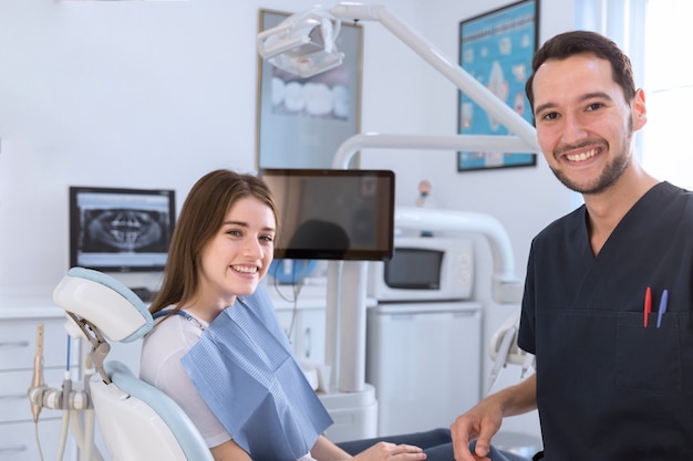 Foto porträt des lächelnden weiblichen patienten und des zahnarztes in der klinik