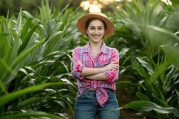 Porträt des Landwirts der jungen Frau, der Maisfeld am sonnigen Sommertag inspiziert.