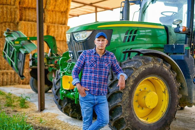 Porträt des Landwirts mit dem Traktor in der Landschaft.