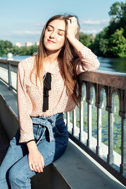 Porträt des langhaarigen blonden Mädchens im Park. Mädchen posiert am Fluss.