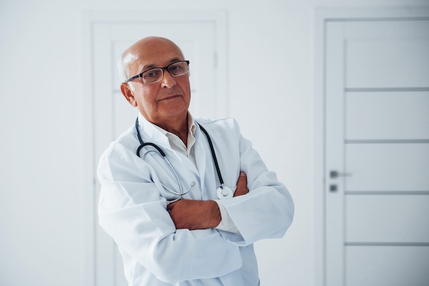 Porträt des leitenden Arztes in weißer Uniform, der in der Klinik steht.
