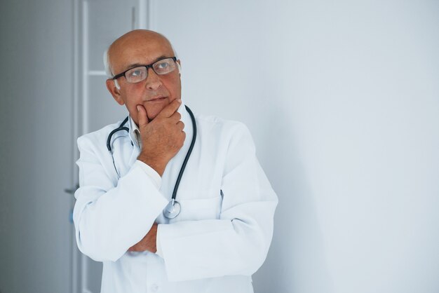 Porträt des leitenden Arztes in weißer Uniform, der in der Klinik steht.