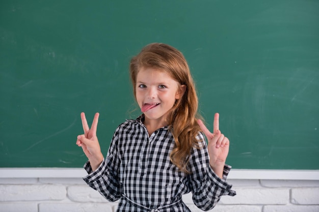 Porträt des lustigen Schülermädchens der Grundschulstudie Lustiges Kindmädchen in der Schule Grundschulkind in der Klasse Spaßzunge Zurück zur Schule