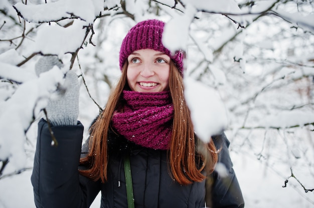 Porträt des Mädchens am schneebedeckten Tag des Winters nahe Schnee bedeckte Bäume.