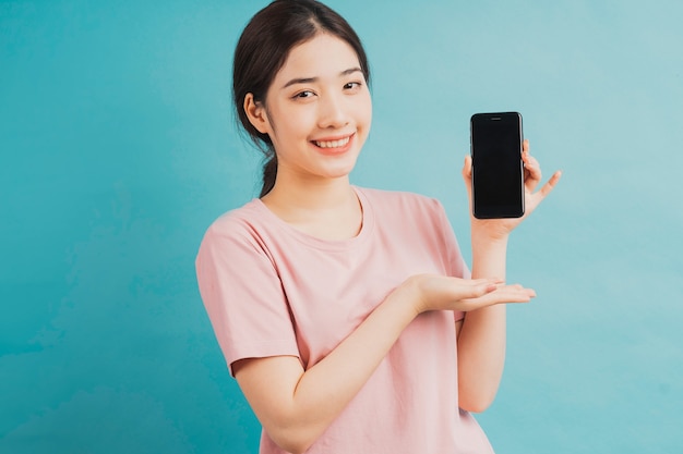 Porträt des Mädchens, das Telefon hält und auf Blau zeigt