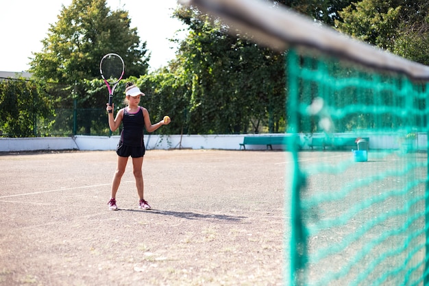 Porträt des Mädchens, das Tennis auf Sportplatz spielt