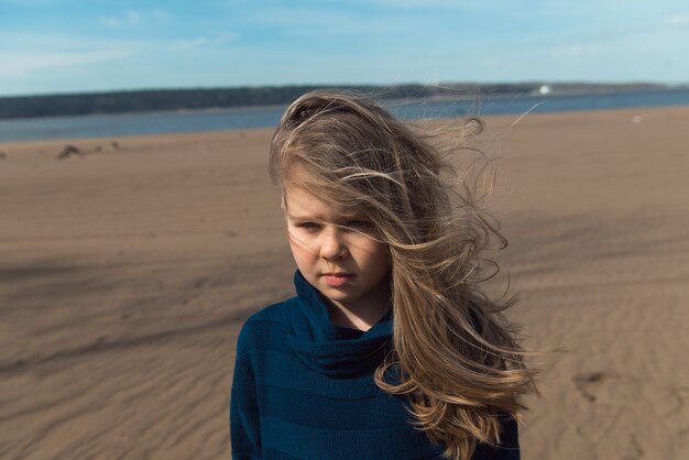 Porträt des Mädchens im grauen Mantel mit Haaren auf Windnahaufnahme