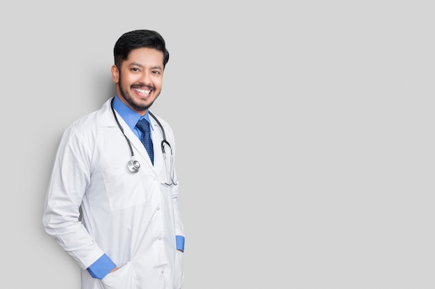 Porträt des männlichen Arztes mit Stethoskop und Armen im Mantel lokalisiert auf weißer Wand. Konzept der Krankenversicherung.