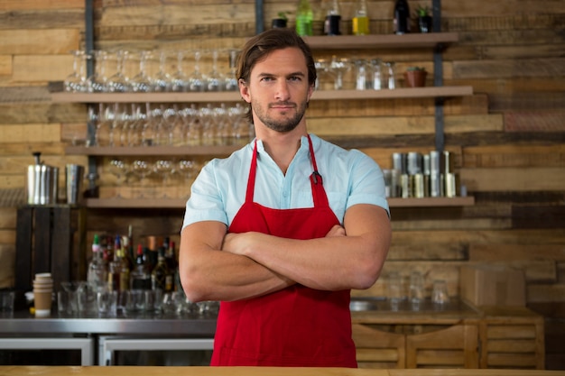 Porträt des männlichen Barista, der Arme im Kaffeehaus verschränkt