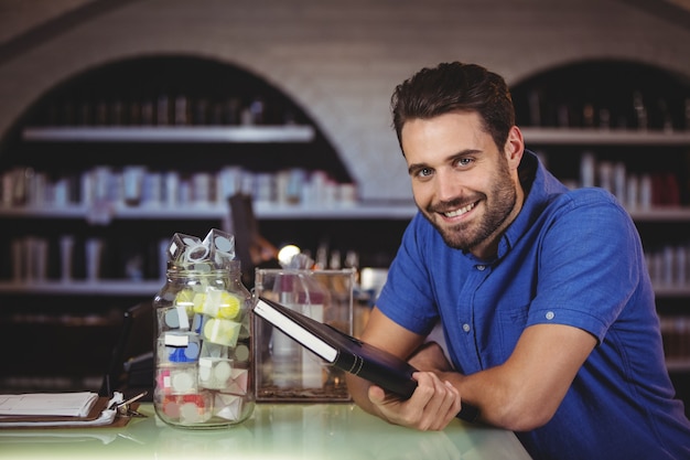 Porträt des männlichen Friseurs, der ein Tagebuch am Friseursalon hält