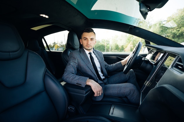 Porträt des männlichen Geschäftsmannes, der am Steuer eines Autos sitzt