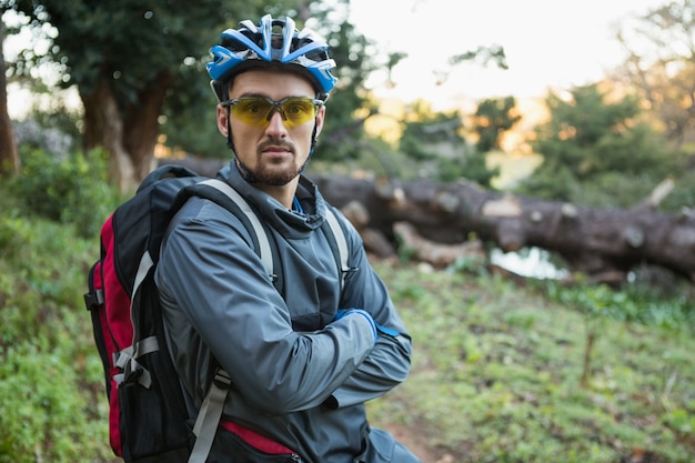 Porträt des männlichen Mann-Mountainbikers mit verschränkten Armen im Wald