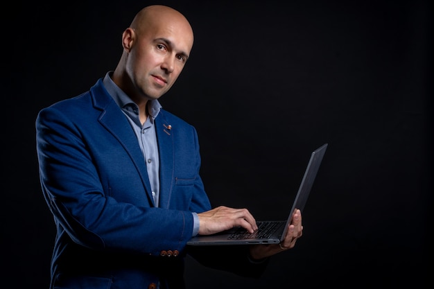 Porträt des Mannes mit Laptop im Studio auf schwarzem Hintergrund