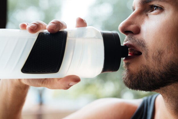 Porträt des Modells im Fitnessstudio mit Flasche hautnah