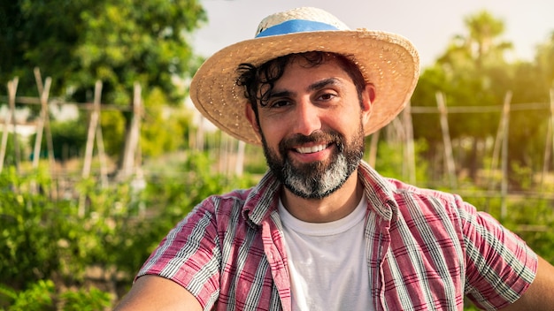 Porträt des modernen bärtigen Bauernmannes macht Pause mit Hacke im landwirtschaftlichen Bereich