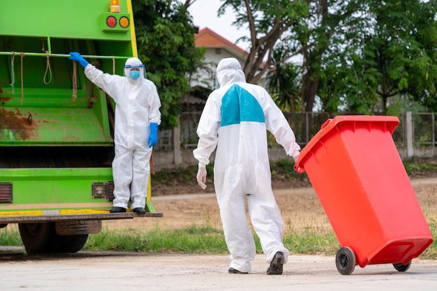 Porträt des müllsammlers in schutzkleidung psa-schutzkleidung tragen medizinischen gummi mit lkw-ladeabfällen und mülleimer, coronavirus-krankheit 2019, coronavirus hat sich zu einem globalen notfall entwickelt.