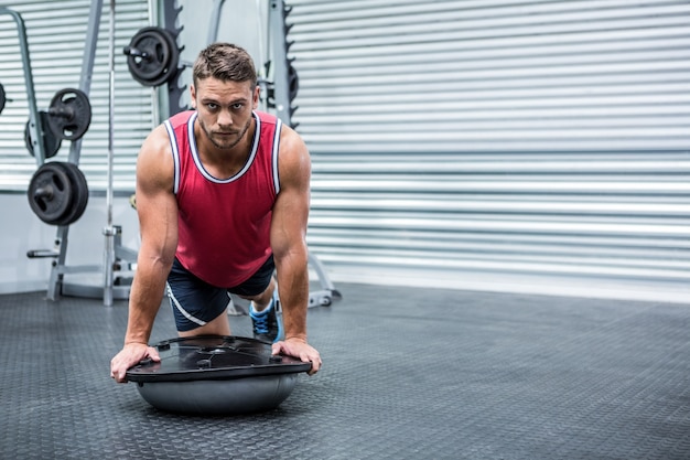 Porträt des muskulösen Mannes, der bosu Ball verwendet