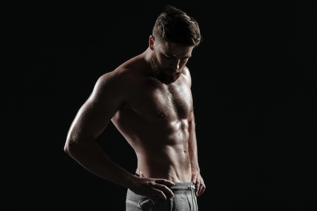 Porträt des nackten athletischen Mannes. isolierter dunkler Hintergrund